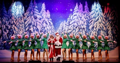 Santa and Mrs. Claus with dancers on a stage during a Christmas show