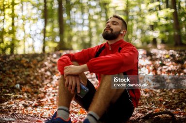 Portrait of relaxed young man with bluetooth headphones in forest
