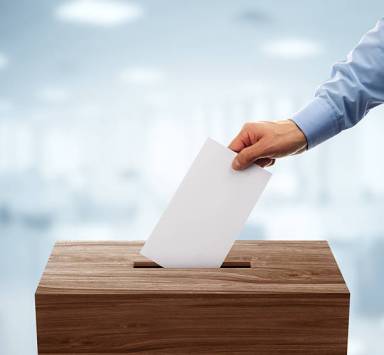 Ballot box with person casting vote on blank voting slip