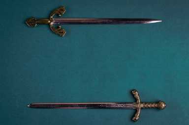Two old knightly swords on a green velvet background.