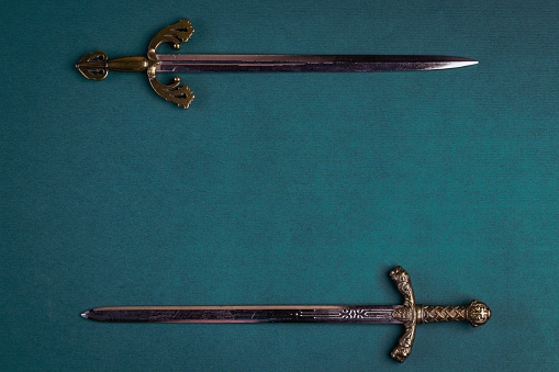 Two old knightly swords on a green velvet background.