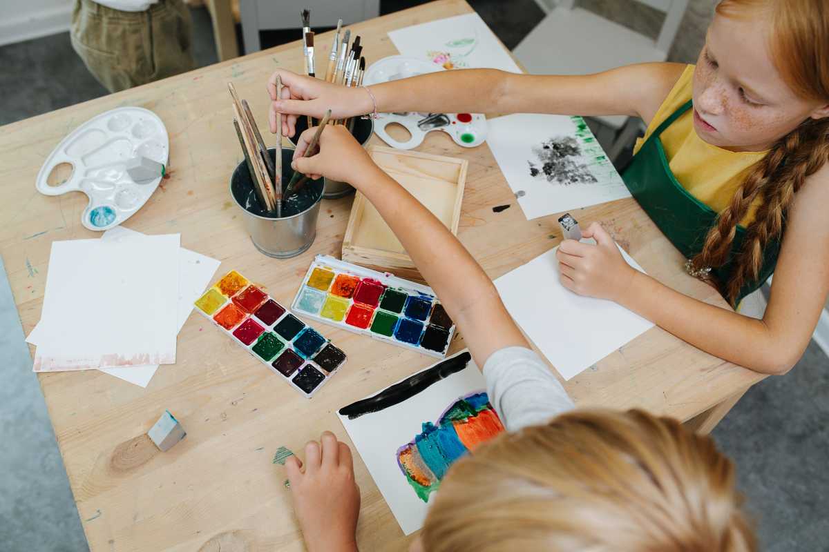 High angle image of kids painting with watercolor. They are keen and competitive