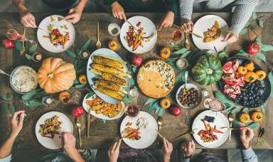 Friends eating at Thanksgiving Day table with vegetarian snacks