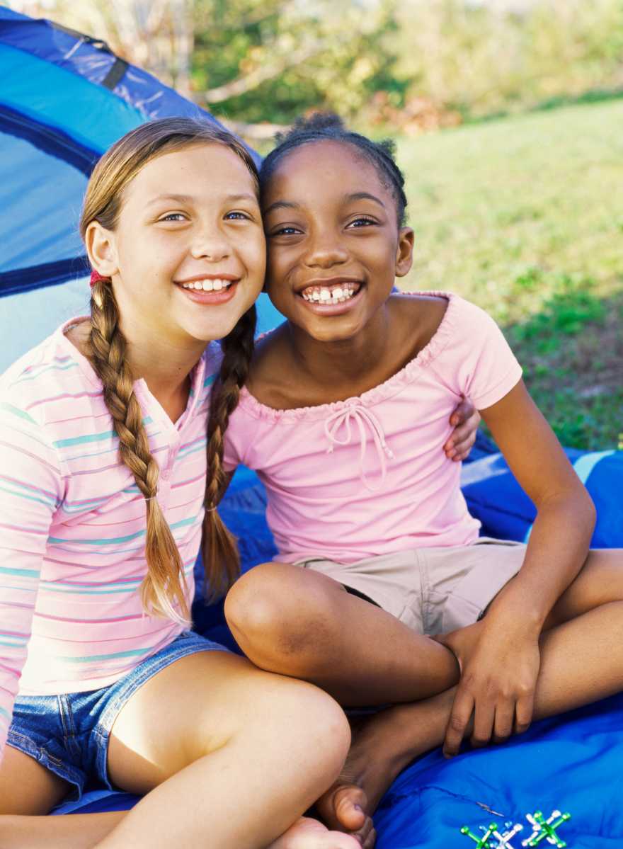 Portrait of two girls outside a tent, smiling